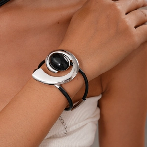 Close-up of double-layer black cord bracelet with oval black stone and spiral silver metal
