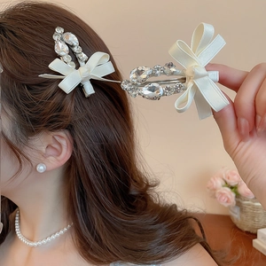 Détail d'une pince à cheveux nœud crème avec strass portée sur les cheveux d'un mannequin
