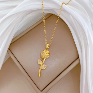Macro view of golden rose flower pendant necklace with diamonds on white silk