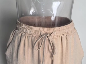 Détail de la taille élastique avec cordon de serrage sur ce pantalon beige
