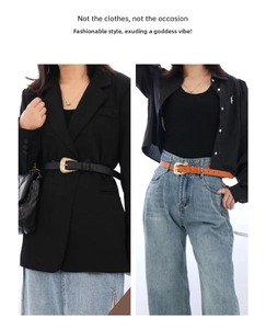 Detail of slim faux leather belts with vintage gold buckles on blazer and denim jeans
