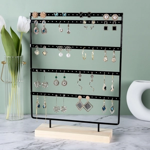 Five-tier black iron earring display stand with wooden base showing jewelry storage