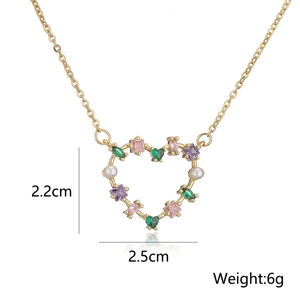 Macro detail of gold-plated heart pendant with stones and pearls, size 2.2x2.5cm