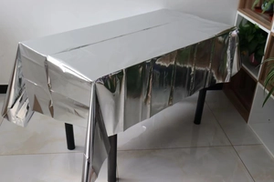 Close-up of shiny silver metallic tablecloth with reflective texture for party decor