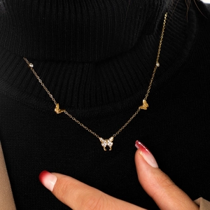 Detail of a gold butterfly necklace with micro-pave diamonds on a black turtleneck
