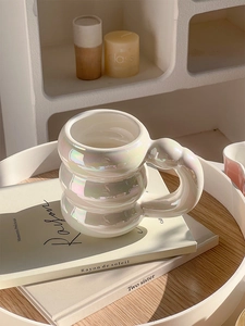 Close-up of pearl white ceramic mug with bubble design and curved handle on a book
