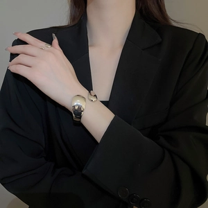 Close-up of polished silver irregular streamline bangle and ring set on model