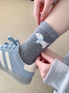 Primo piano di calzini grigi in cotone con motivo a cucciolo bianco e fiocco blu decorativo
