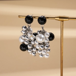 Detail of dark pearl and silver beaded earrings in cluster style on a golden stand
