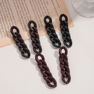 Detail of matte black and dark brown acrylic link chain earrings on a vintage paper