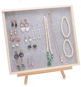 Macro view of grey velvet jewelry display board with earrings and necklaces on easel