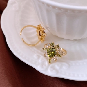 Close-up of 14k gold plated ring with heart-shaped olive green zircon and white crystals