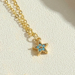 Detailed shot of golden star pendant with inlaid blue cubic zirconia on a delicate chain