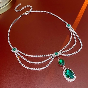 Close-up of layered silver necklace with emerald-style green gemstones and lobster clasp