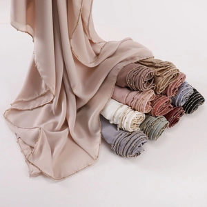 Beige chiffon hijab with metallic beads shown alongside a variety of colorful scarf rolls