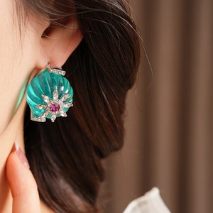 Close-up of vintage flower stud earring with turquoise stone and crystal on model