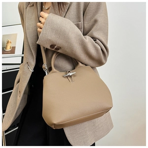 Detail of khaki leather bucket bag featuring bamboo clasp and lychee grain texture
