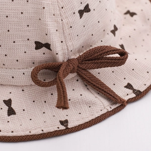 Macro detail of baby sun hat with brown polka dots and a 3D knitted bow decoration