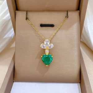 Close-up of heart-shaped green crystal necklace with diamond floral detail in gold finish