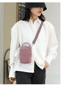 Pink nylon crossbody mini bag worn by model with adjustable strap and zip layers
