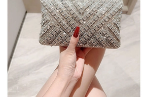 Close-up of a silver evening clutch bag with sparkling crystals held by a hand