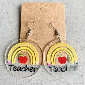 Detail of acrylic teacher earrings with apple and pencil rainbow design on display card
