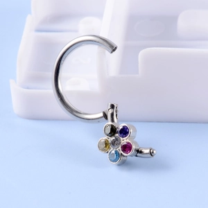 Macro shot of curved stainless steel navel ring with colorful six-petal zircon flower charm
