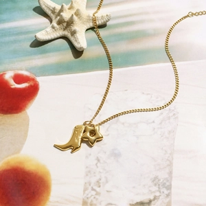 18K gold plated stainless steel necklace with boot and star pendants on beach background