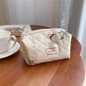 Close-up of quilted cotton makeup bag with bear print and zipper on wooden desk