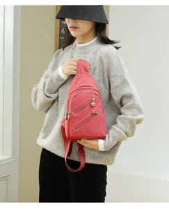 Detail view of pink nylon crossbody bag with multiple zipper pockets on a model