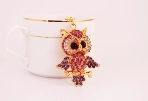 Macro shot of owl keychain featuring pink and purple rhinestones on a gold metal base