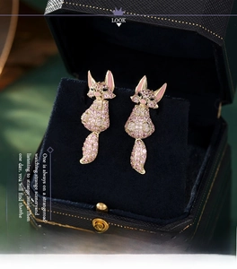 Macro shot of gold fox earrings with pink crystals in a black jewelry box