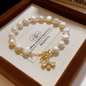 Macro shot of freshwater pearl bracelet with gold bee pendant and toggle clasp detail