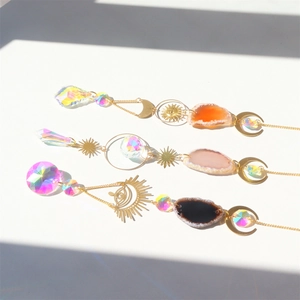 Three crystal suncatchers with agate slices and moon sun prisms on a white surface