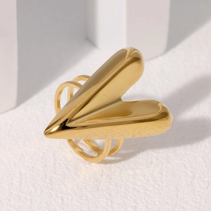 Minimalist gold 3D heart-shaped ring in polished stainless steel on a white stone background
