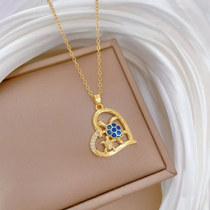Detail of gold heart pendant with blue jeweled turtles on beige jewelry box with white fabric