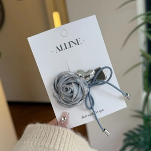 Detail of elegant grey-blue silk rose hair tie with silver heart charm on card