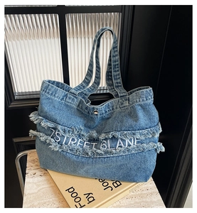 Détail du sac cabas en denim bleu délavé avec bords frangés et broderie blanche 7 Street