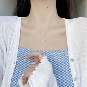 Silver lock pendant necklace with blue heart zircon on female model's neck