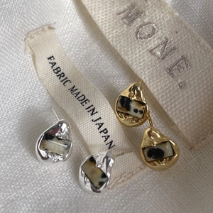 Macro view of irregular silver and gold stud earrings with dalmatian stone textures
