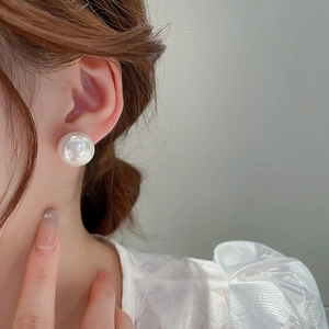 Gros plan d'une boucle d'oreille en perle blanche portée avec des détails élégants