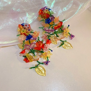 Dettaglio di orecchini floreali fatti a mano con petali di acrilico e perline colorate