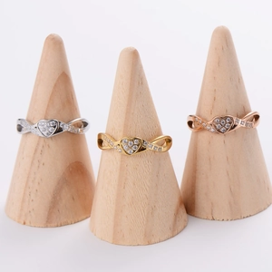 Trio of heart and infinity rings in gold, silver, and rose gold on wooden displays
