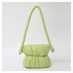 Close-up of light green puffer bucket bag featuring soft quilted texture and knotted strap