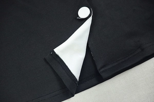 Detailed close-up of high-quality black knit fabric with contrasting white buttons and seams