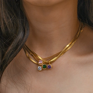 Close-up of a layered gold snake chain necklace with colorful zircon pendants on a model