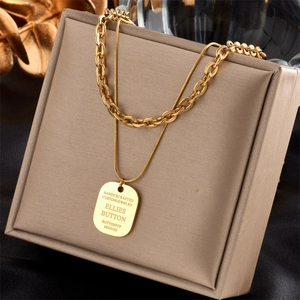 Detail of layered gold link chain necklace with handcrafted engraved pendant on silk box