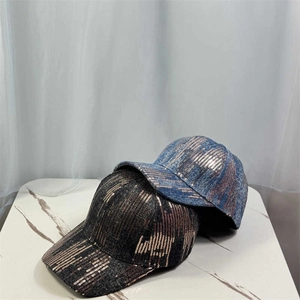 Close-up of sparkling sequin baseball caps in blue and bronze on marble surface