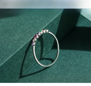 Détail macro d'une bague en argent ornée d'une rangée de zircons arc-en-ciel