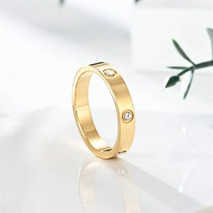 Detail of a gold clover ring with three small sparkling crystals on a white surface